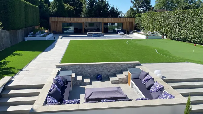 Landscaped garden with sunken seating area, lawn, putting green and timber-clad garden building