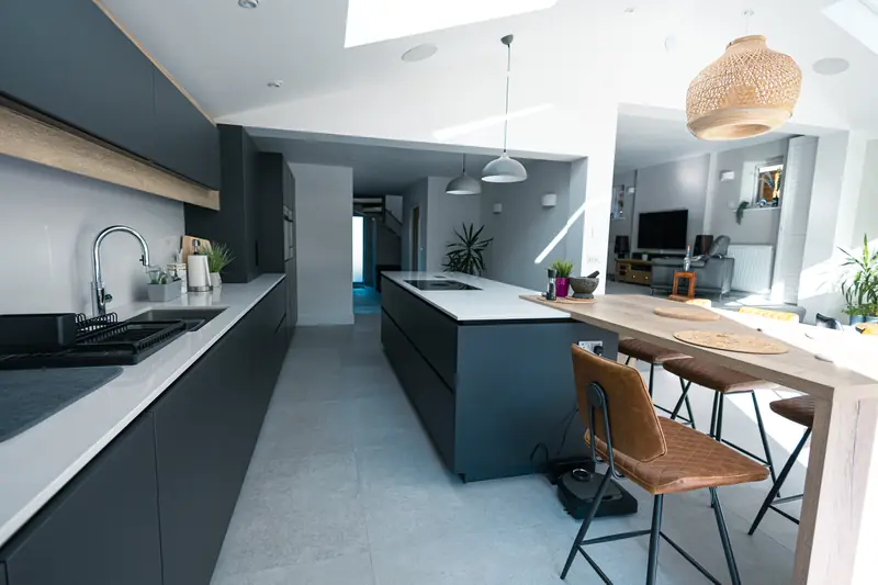 Long galley run of dark kitchen units opening into the living area